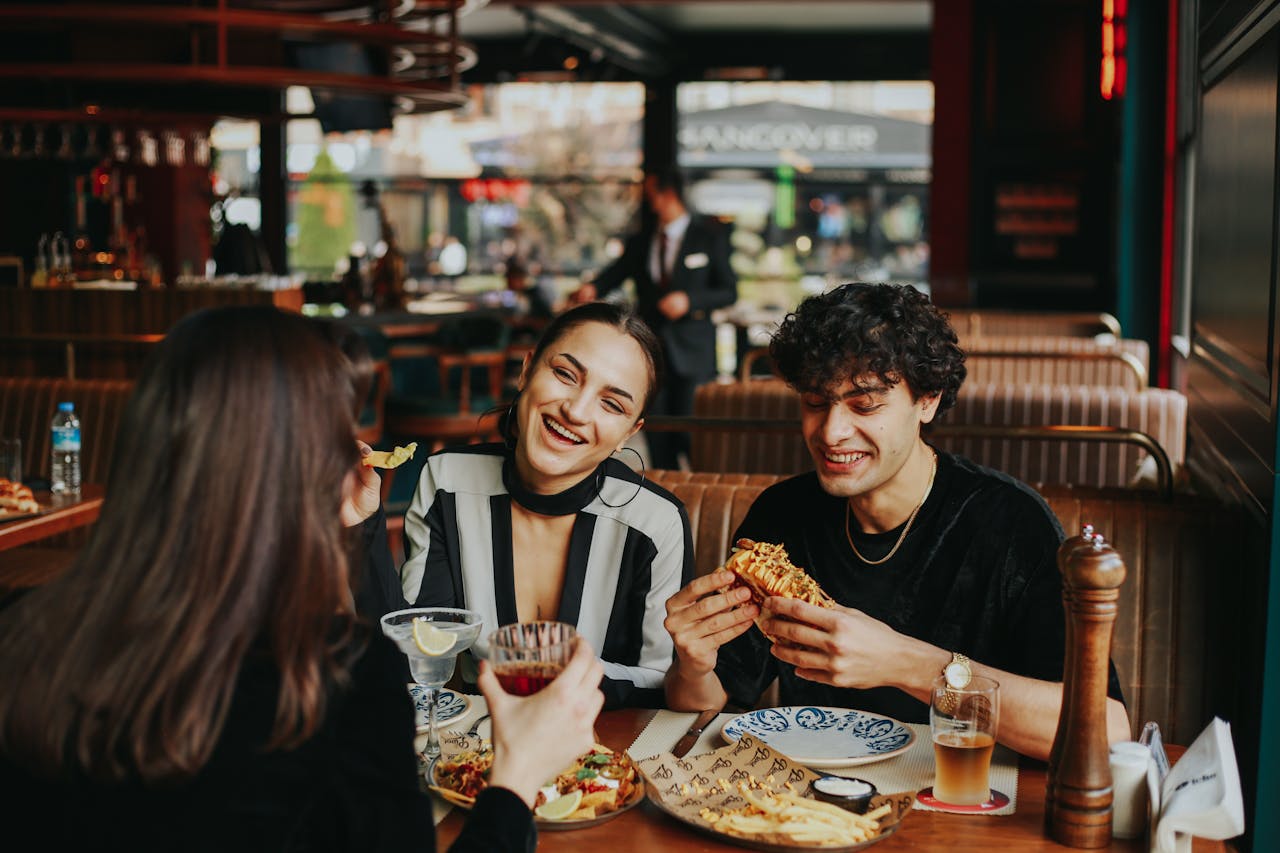 Group of three young friends have a conversation over a meal in a casual dining restaurant